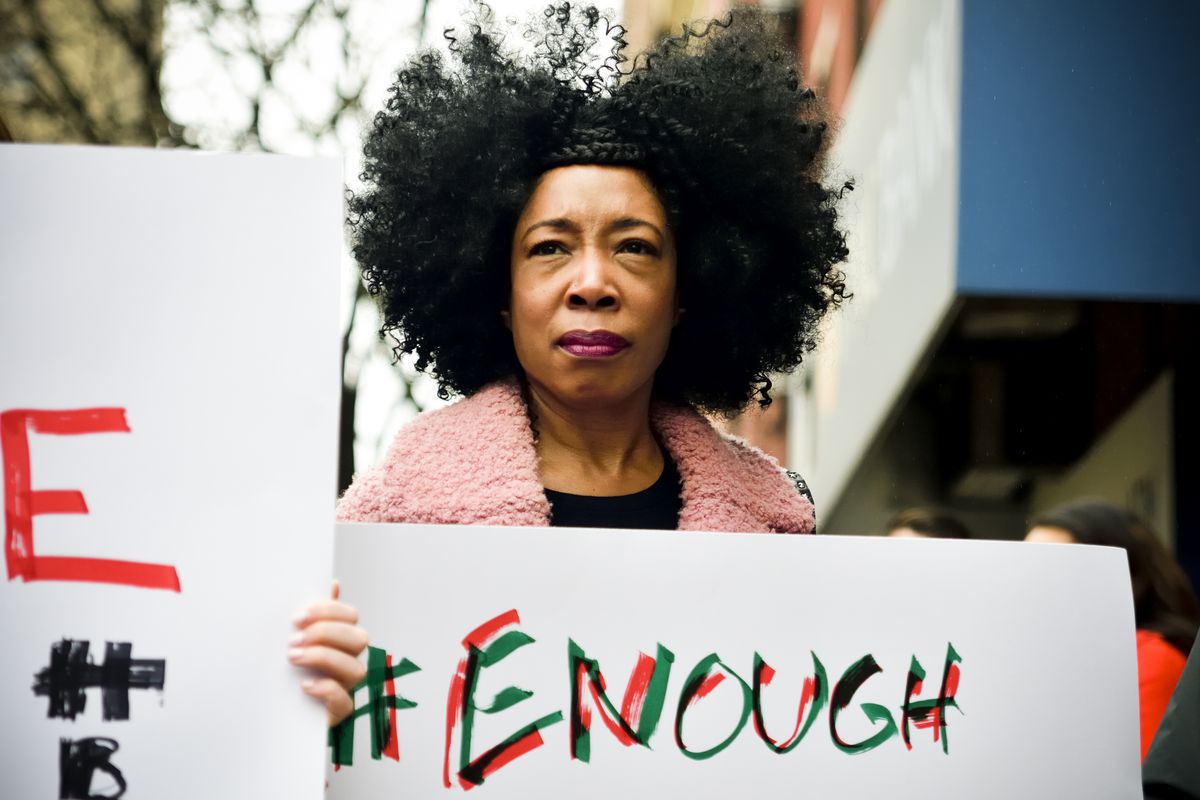 Woman holding sign that says enough