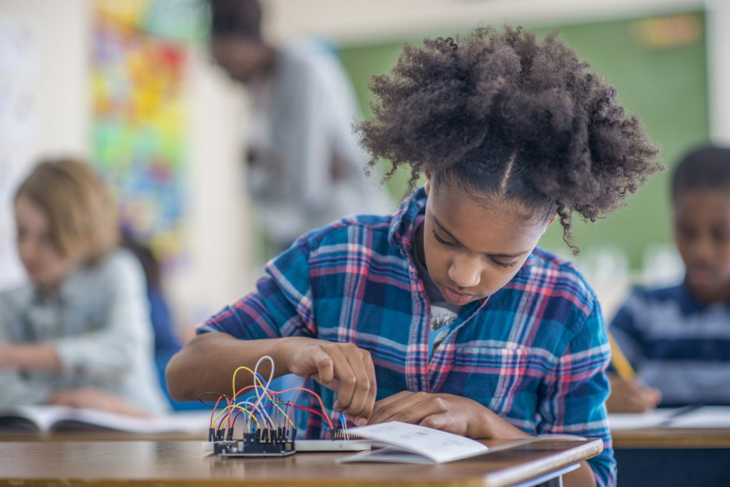 student doing a science experiment with wires and circuits.