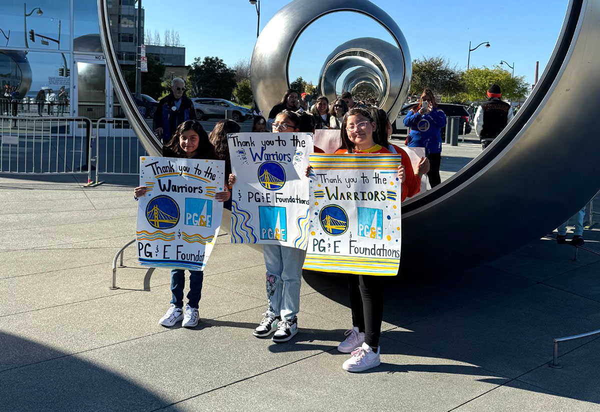 three girls with signs for the warriors game